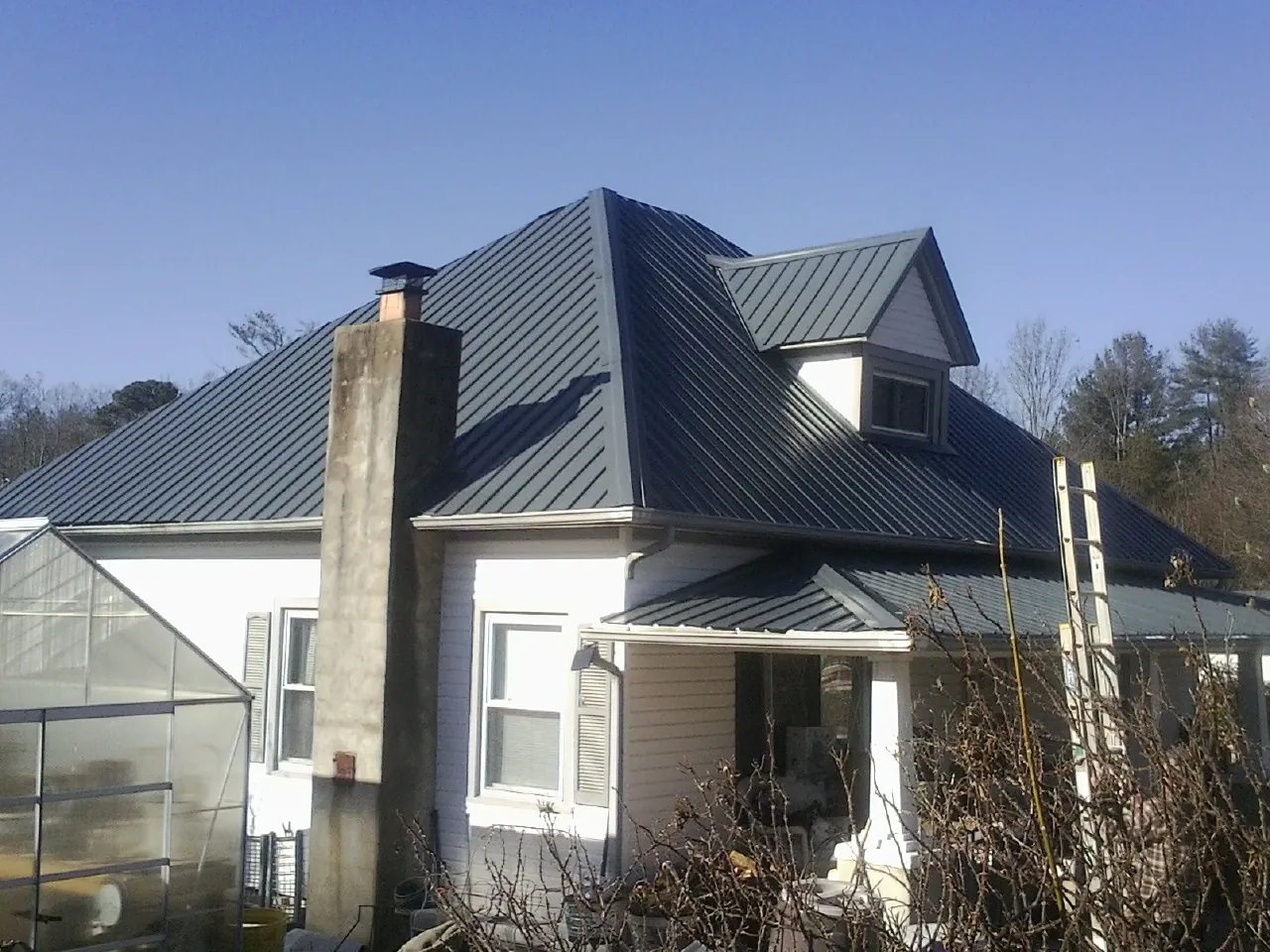 Dark blue standing seam metal roof on a white farmhouse with dormer — Slate & Tile Roof Repair by Roofing Brothers in Helenville