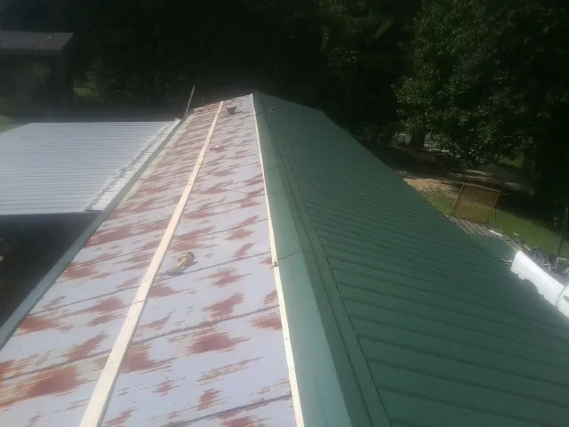 Old rusted panels beside newly installed green metal roofing — Wind Damage Roof Repair by Roofing Brothers in Helenville