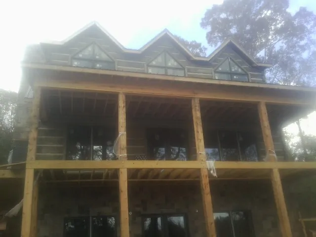 Dormers and porch framing on a large log home under construction — Roof Coating work by our crew in Helenville