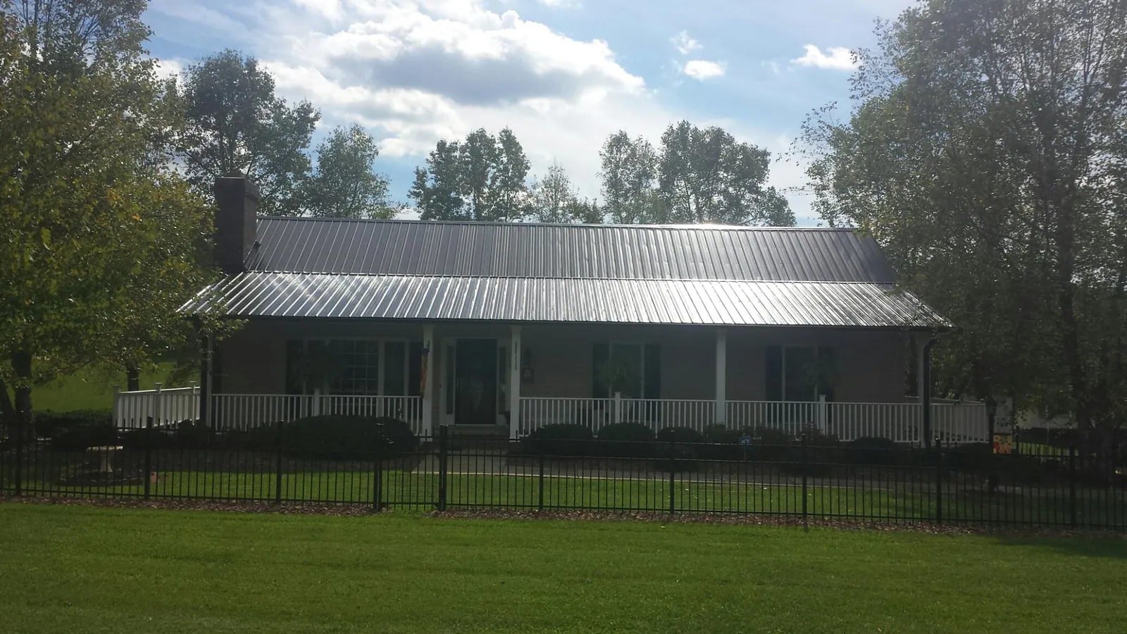 Gray metal roof on a brick ranch with a full width front porch — Gutter Guard Installation work by our crew in Helenville