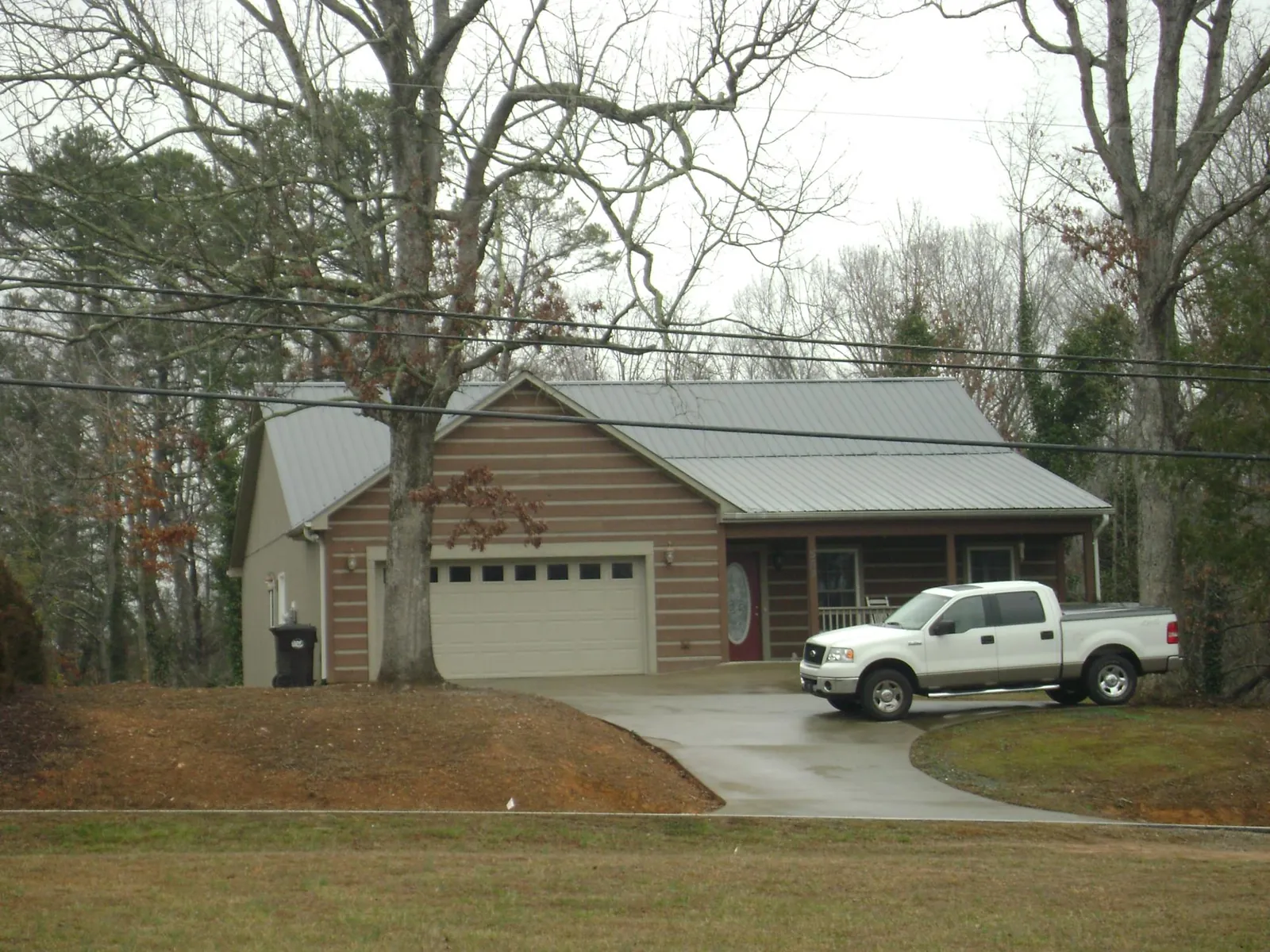 Gray metal roof on a log sided house with an attached two car garage in Helenville
