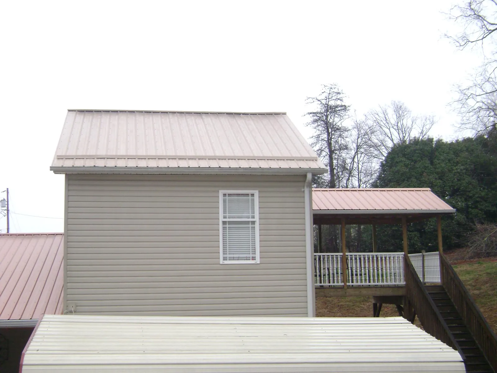 Tan metal roofs on a two story addition and attached porch, from a Roof Replacement job in Helenville