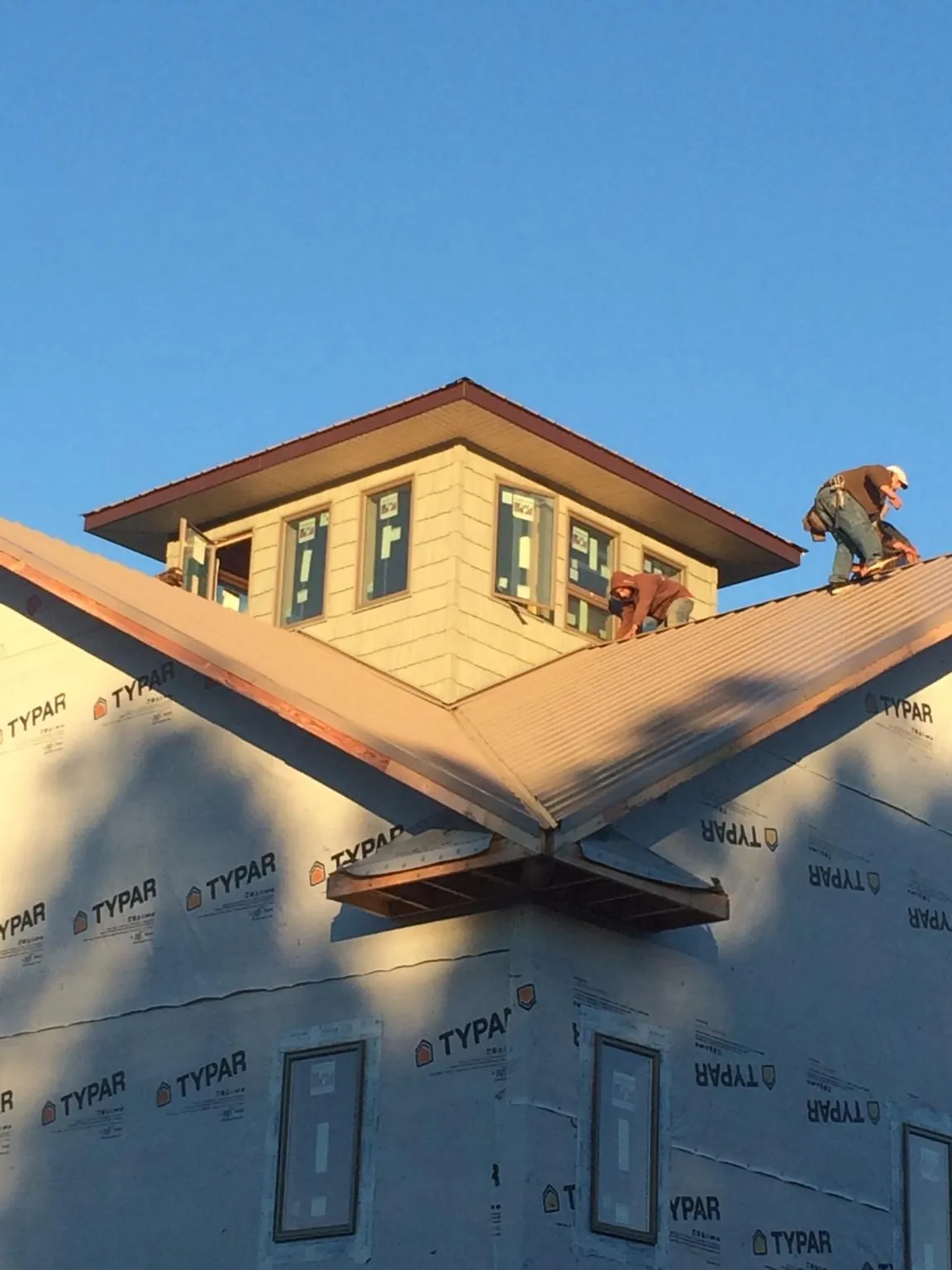 Roofers working around a rooftop cupola on a new metal roof at sunset — Roof Waterproofing in Helenville by Roofing Brothers